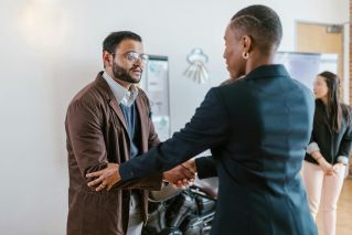 Business professionals greeting with a handshake in an office setting, promoting teamwork and cooperation.